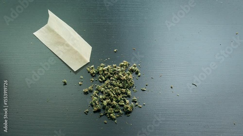 Male hands filling a rolling paper with cannabis marijuana, in preparation of a joint.