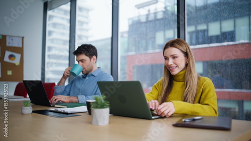 Friendly coworkers working laptops at office space closeup. Man woman managers
