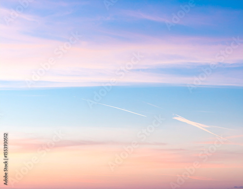 Serene sky painted in soft hues of pink and blue, with delicate streaks of vapor trails adding touch of wonder to tranquil atmosphere
