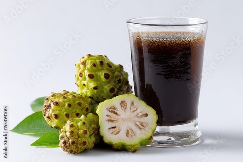 A focused shot of noni juice in a glass on a white surface featuring slices