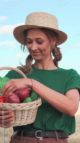 Woman smiles while holding a basket filled with colorful vegetables in a sunny outdoor area. She enjoys her time surrounded by nature and fresh produce, embracing a healthy lifestyle.