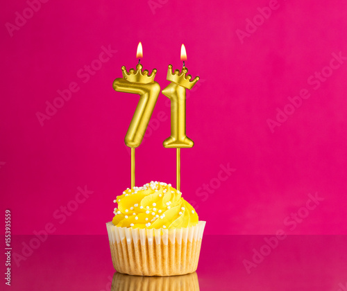 Birthday celebration with number 71 candle - Yellow cupcake on a pink background