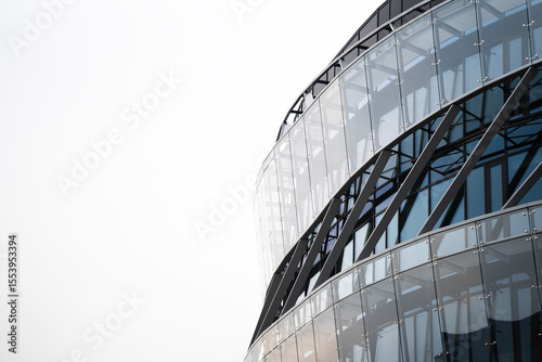 Contemporary office building with a curved glass facade, featuring steel structural elements. The image highlights modern architecture and urban design for commercial property use.