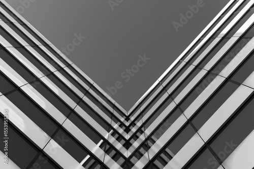 Black and white photo of a modern glass building corner, viewed from below. Emphasizes symmetry, architecture, and urban design for architectural reference.