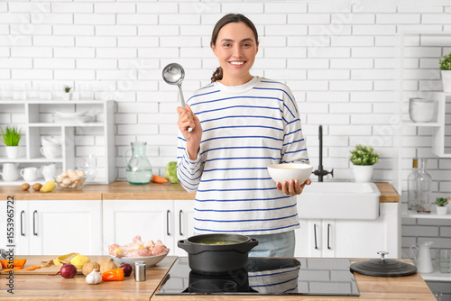 Young woman pouring soup in...