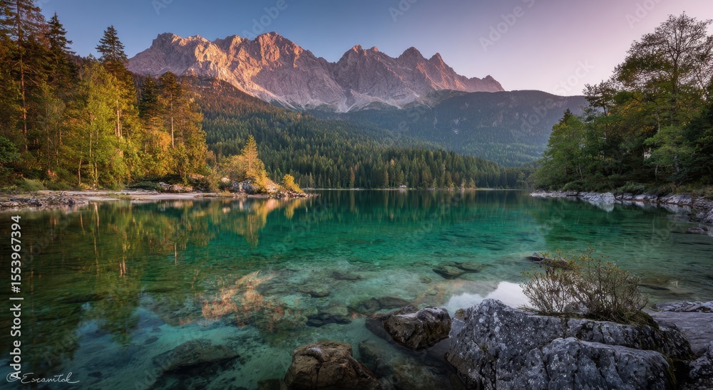 Fototapeta premium Serene mountain lake at sunrise reflecting peaks and lush trees, ideal for nature enthusiasts