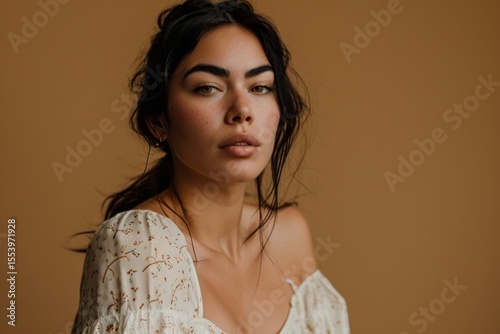Portrait of a beautiful young woman in a white dress on a brown background