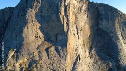 Majestic rocky mountain face bathed in sunlight and shadow creating dramatic texture