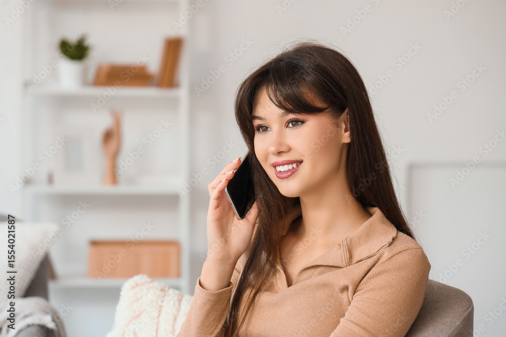 Smiling young woman talking by mobile phone in armchair at home, closeup Smiling young woman talking by mobile phone in armchair at home, closeup