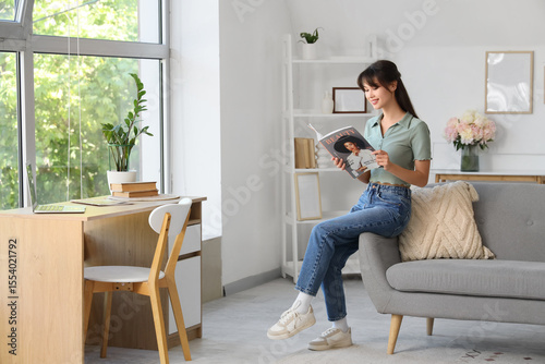 Smiling young woman reading...