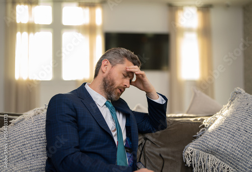 Sad man with laptop got migraine touches her head because of pain. Man manager with strong headache. Overworked freelancer or manager at office.