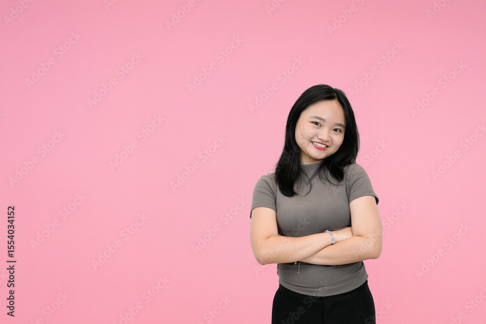 confident young asian woman in crossed arms in pink studio background confident young asian woman in crossed arms in pink studio background