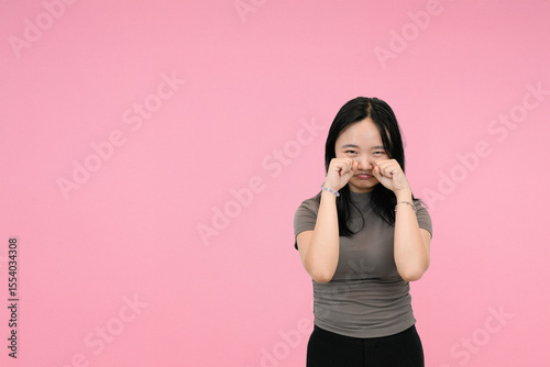 cute asian girl making ad sad expression in pink studio background