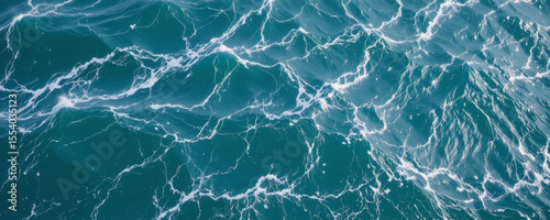 Ocean water surface with white foam patterns and waves creating dynamic and natural marine texture in deep blue color