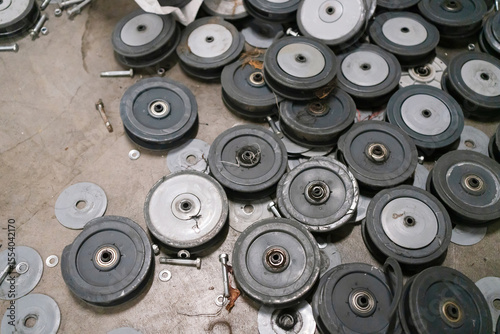 Close-up shot of multiple damaged black rubber wheels with bearings, scattered on a surface with some metal components visible. photo