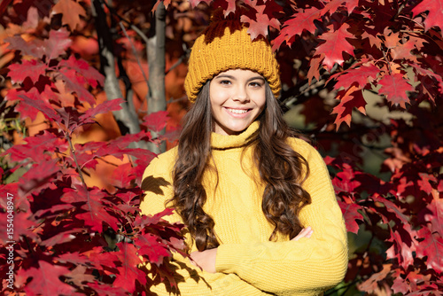 Child teen girl in autumn fall park outdoor, autumn fun kids face. cheerful teen girl in hat at autumn leaves on natural background