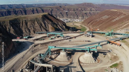 Aerial view of a large industrial site with machinery and transportation in a mountainous landscape