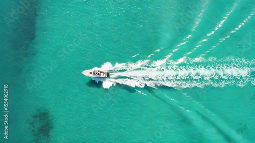 Aerial View of a White Motorboat Sailing on Bright Turquoise Sea Water Creating a White Wake on Sunny Day