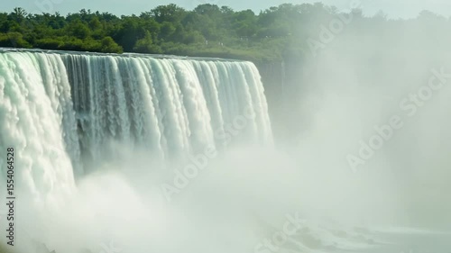 Majestic waterfall cascading amidst lush greenery and mist