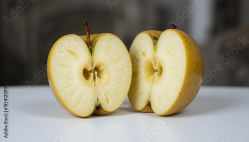 Two halves of a golden apple showcase the juicy flesh and core details on a clean white surface for a fresh, organic presentation.