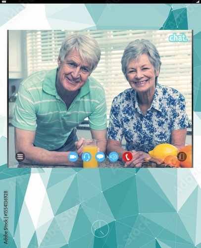 Senior couple leaning on counter smiling with juice, fruit basket in call frame on teal backdrop