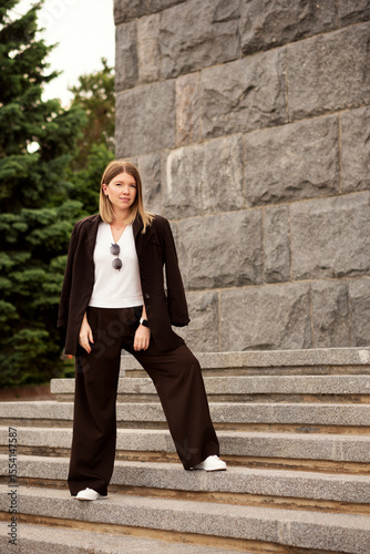 Young woman confidently standing on stone staircase, outdoors portrait.