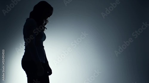 Dramatic silhouette of a person with head bowed, conveying sadness, despair, and emotional struggle against a dark background.