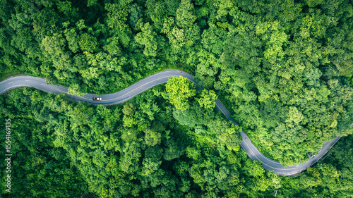 Aerial view of a road in the middle of the forest , road curve construction up to mountain