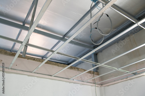 Interior renovation project shows progress with electrical wiring installation within new aluminium ceiling framework. detailed look at building construction and design work