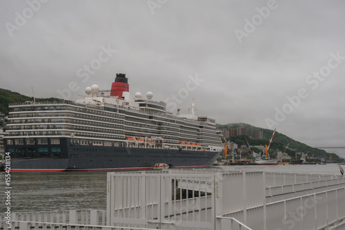 Classic ocean liner cruiseship cruise ship Elizabeth in port of Nagasaki, Japan with skyscraper downtown city skyline during summer Honshu circumnavigation cruising for cherry blossom bloom