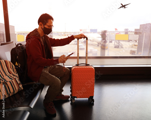 Travel trip with asian young man and backpack as looking the airplane in the hall room with sunlight in the airport terminal