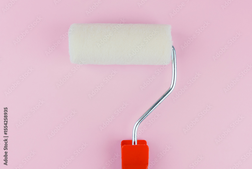 Obraz premium Single red handled roller on pink background for simplicity and home painting concept