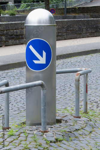 A metal pole in the middle of the roadway, enclosed by a steel frame for safety and bypassing