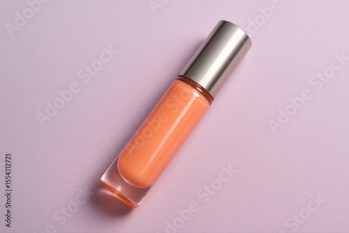 An orange lip gloss with silver cap on a light purple background view