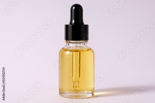 Close up of a glass bottle with yellow liquid and a black dropper top