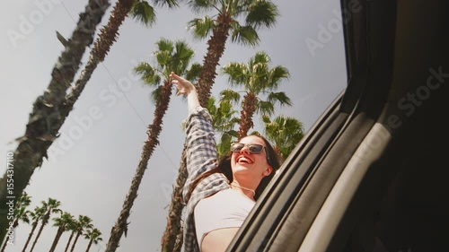 Excited woman in the window of a rental car, hair moving in wind