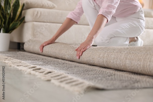 Fotografie Woman putting new rug on floor at home, closeup