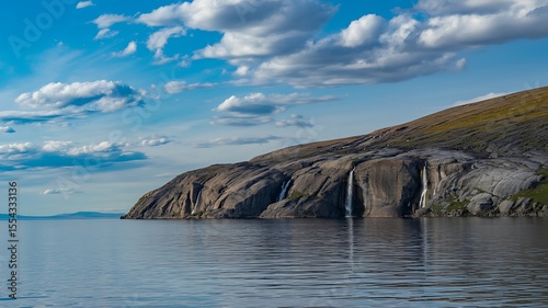 Tranquil waterfall landscape with rocky cliffs and fluffy clouds  
