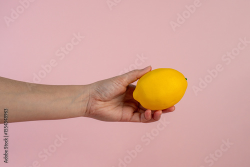 Lemon fruit in hand isolated on pink background.
