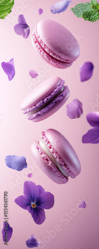 Pink macarons with flowers and mint leaves on a pastel background