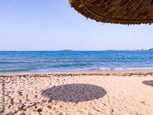 Beach, sea, empty sky and island in the distance