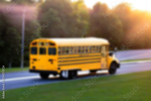 blurry photo of yellow school bus in the morning with sunrise in the bright sky