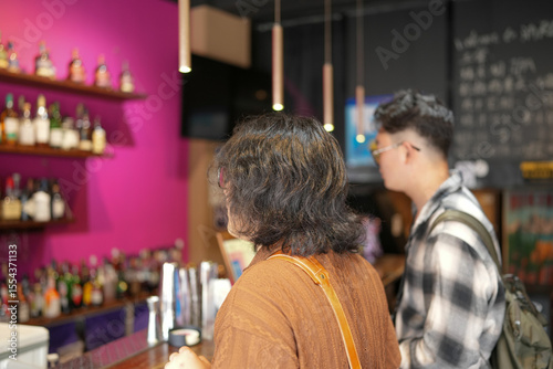 Photography Two young Chinese men in their early twenties, both wearing glasses, are seen ordering drinks together at a stylish cafe