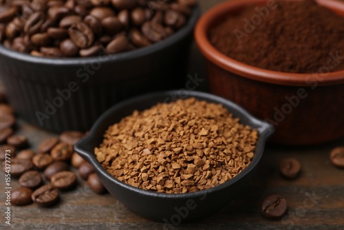 Different types of instant coffee and beans in bowls on wooden table, closeup