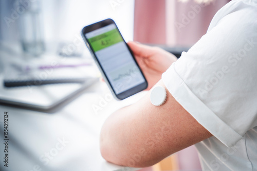 Woman using smartphone to monitor blood sugar levels with a wearable sensor