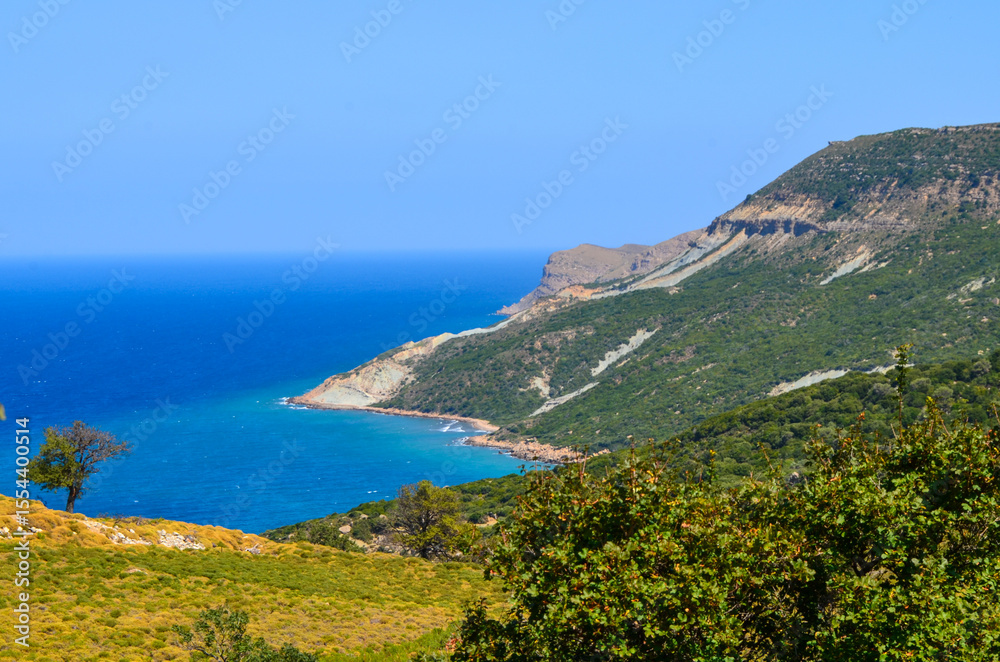 Fototapeta premium A beautiful blue ocean with a mountain in the background. The sky is clear and the sun is shining