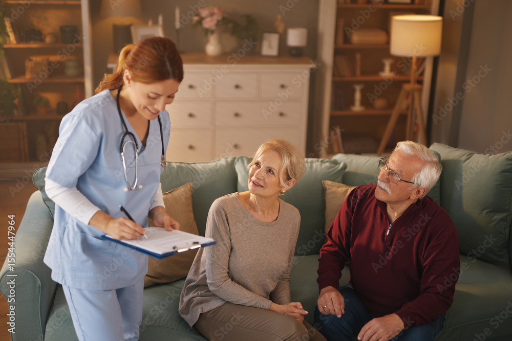 Obraz premium A female nurse in blue scrubs takes notes on a clipboard while talking to an elderly couple who are sitting on a sofa in their living room, discussing health and medical needs.