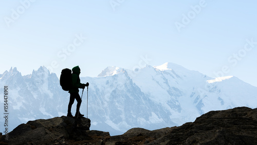 Silhouette of a tourist with a backpack against the background of high snow-capped mountains. Travel and adventure concept
