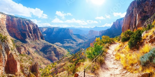 A scenic mountain trail winds through a sunlit valley with cliffs, vibrant foliage, and a bright sky filled with clouds.