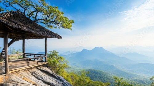 A wooden pavilion overlooks a scenic mountain range under a bright blue sky with light clouds.